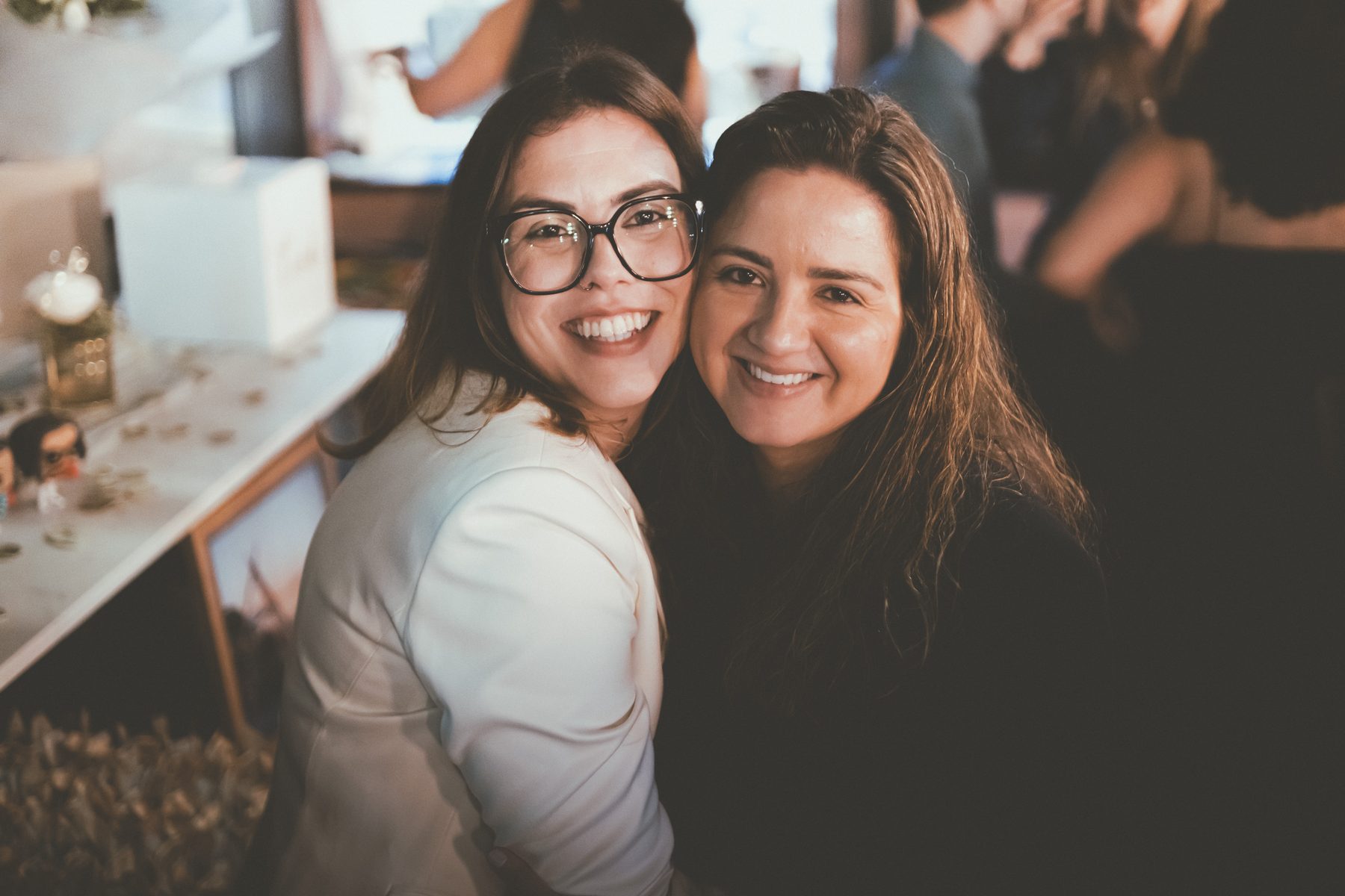 Two brides cheek to cheek, laughing at their wedding