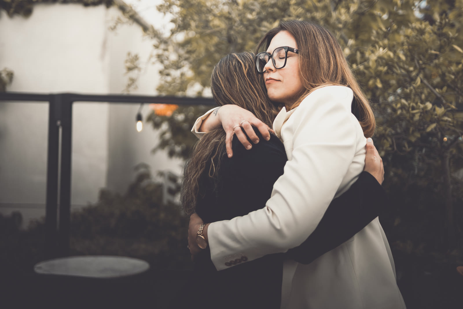 Two brides holding each other close, eyes shut, on their wedding day