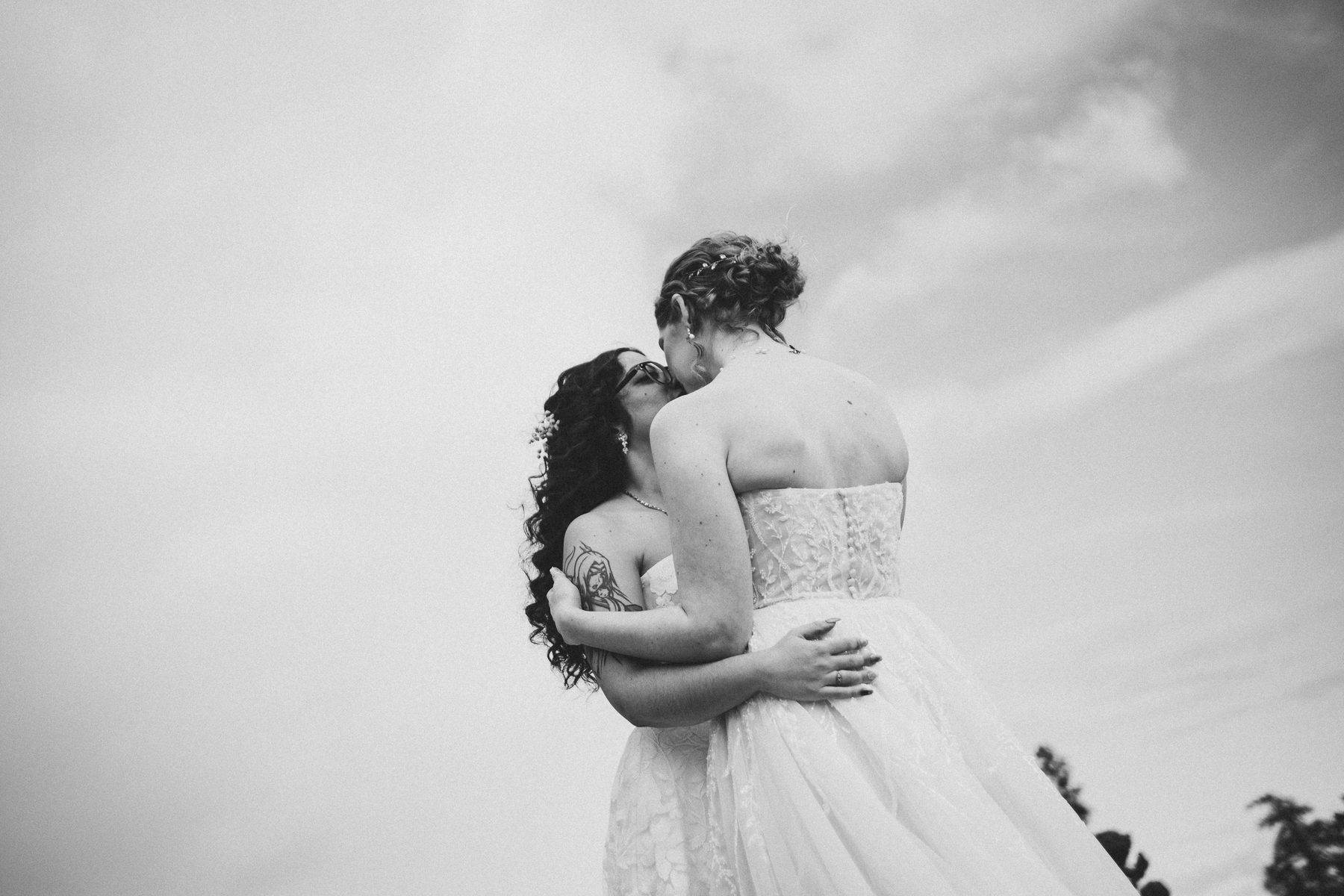 Two brides kissing in their wedding dresses