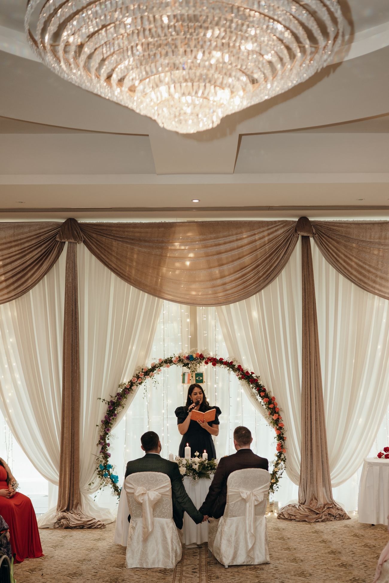 A decorated wedding venue with draped arch and chandelier